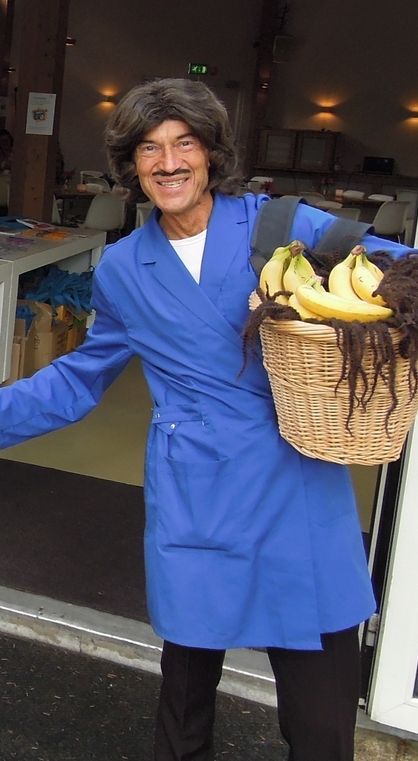 Schoonmaker met mand bananen onder de arm helpt handje mee in de dierentuin.