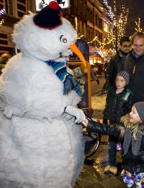 Typetje sneeuwman geeft een hand aan een meisje.